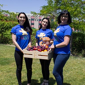 Staff of Eminence Kids partner in Madera California outside holding HANK bear and crate of organic produce